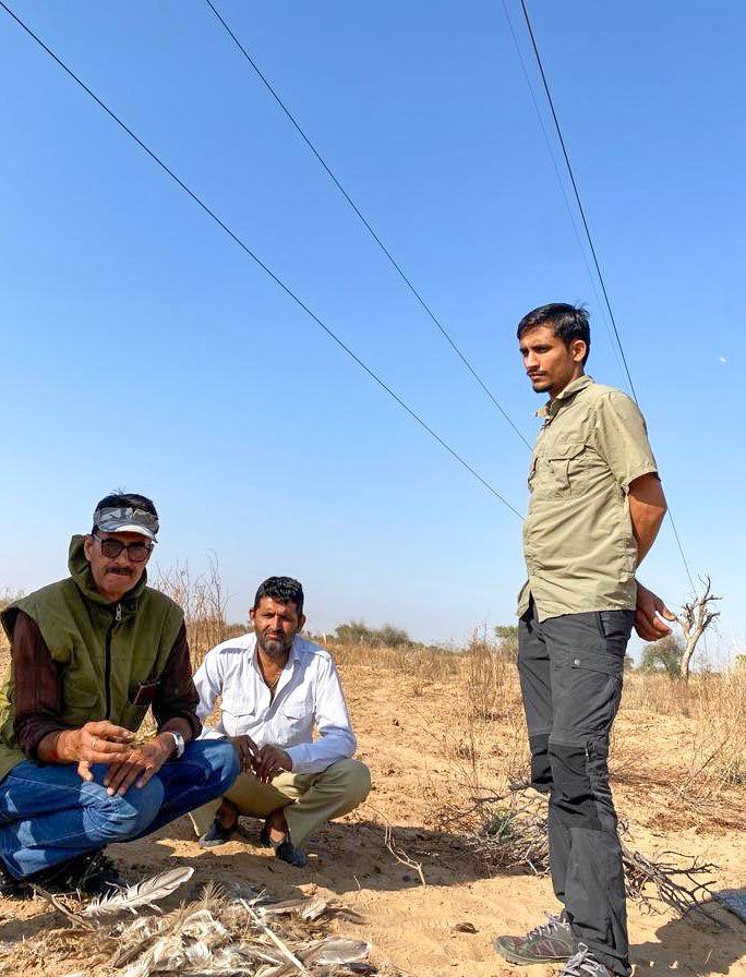 Radheshyam (standing) and local Mangilal watch Dr. S. S. Rathode, WII veterinarian (wearing a cap) examine the feathers. Photo: Priti David/PARI