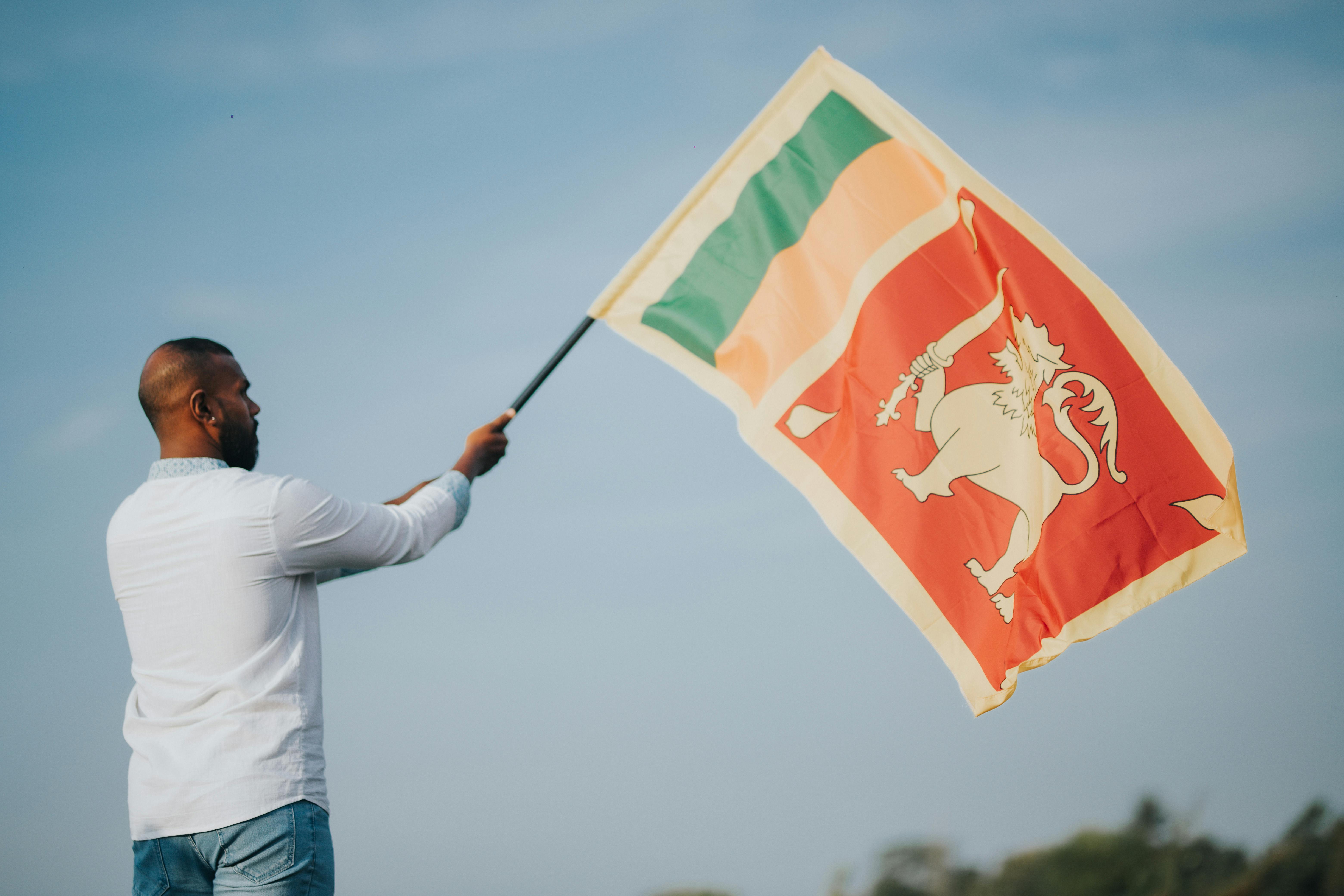 A man waving the Sri Lankan flag. Photo: Chathura Anuradha Subasinghe via Pexels