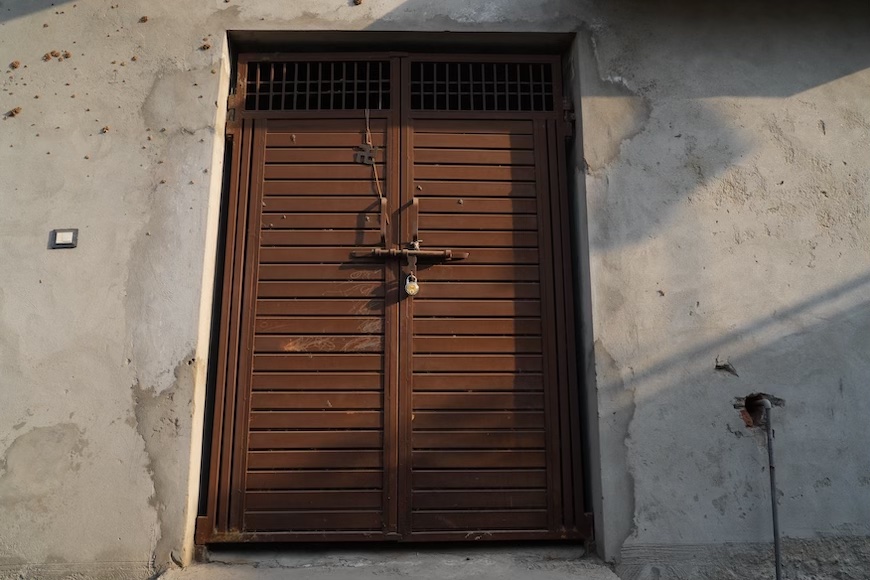 Image of a closed brown door in Uncha Amirpur village, representing the unheard pleas of the residents against the power plant and the suffering it is causing them. Photo: Suhail Bhat.