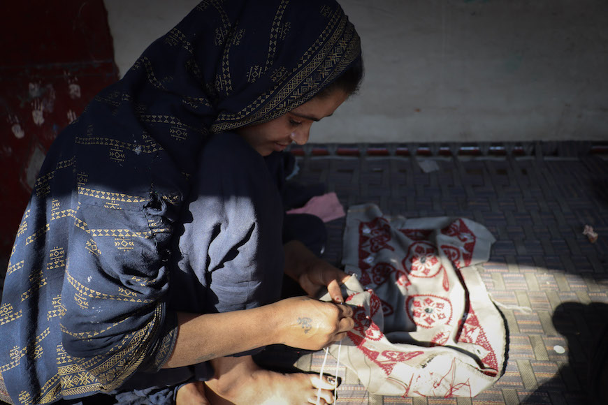 A Pakistani Hindu refugee woman weaves a pillowcase, threading hope into every stitch inside her makeshift home in the Majnu-Ka-Tilla refugee colony.