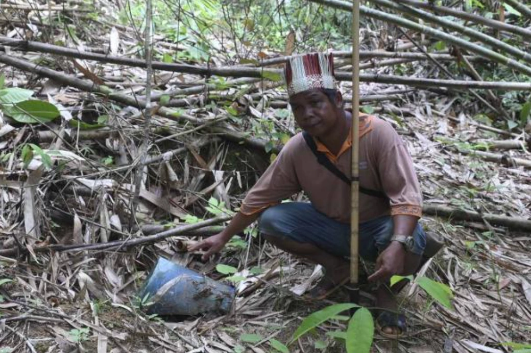 A villager showing a grave. They also bury old knives in a bucket at the grave. Many burial grounds were encroached, they say. Photo: Malaysiakini