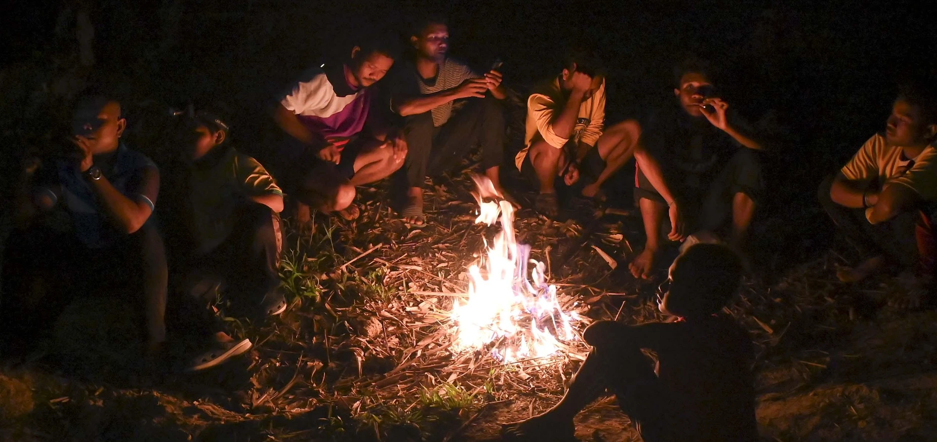 Temiar men gathering around a bonfire on a pitch-black night. Photo: Malaysiakini