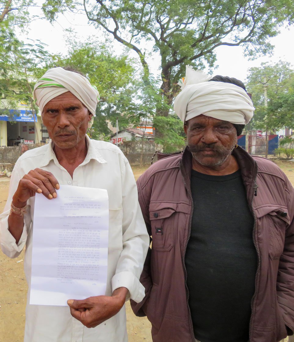 Sangeeta’s father holding up the complaint of abandonment that his daughter filed. Sarpanch Joga (in brown) has come along for support. Photo: Priti David/PARI