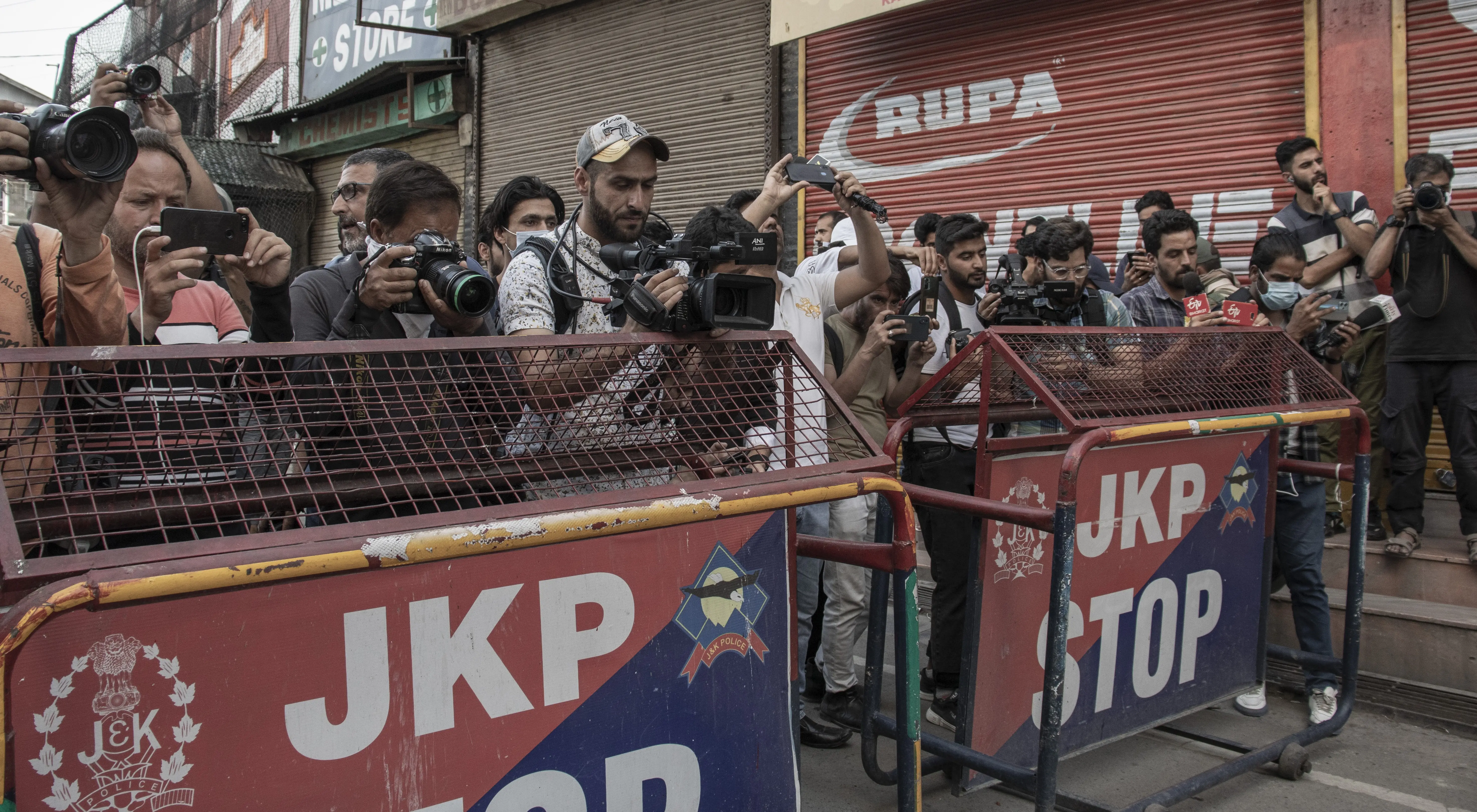 Journalists in Indian-administered Kashmir report from behind a barricade in 2022. Photo: Zainab