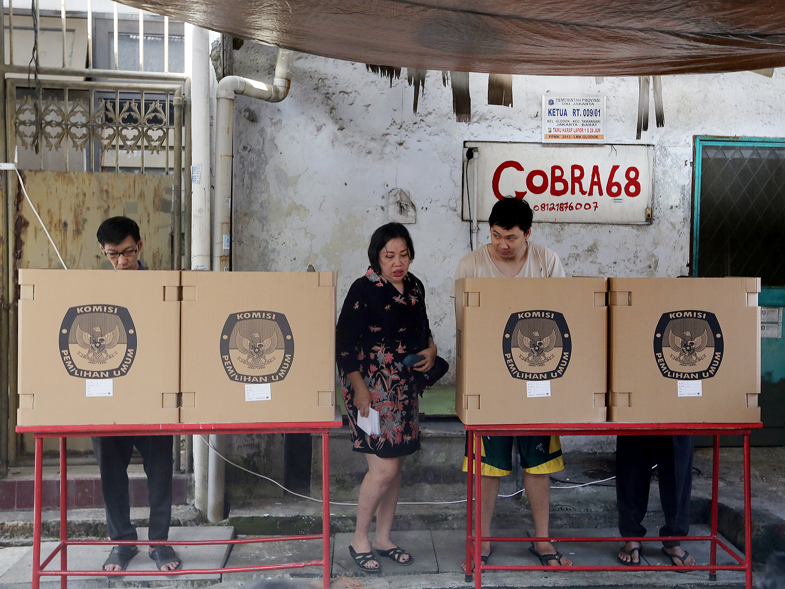 Chinese-Indonesian citizens participate in the 2014 General Elections in Glodok, Jakarta’s Chinatown and one of the tensest areas during the May 1998 riots. The high fences and iron security bars commonly installed on the windows of Chinese-Indonesian homes and shops since the riots remain a visible manifestation of the community’s lingering trauma. Photo: Ricky Yudhistira/Project Multatuli