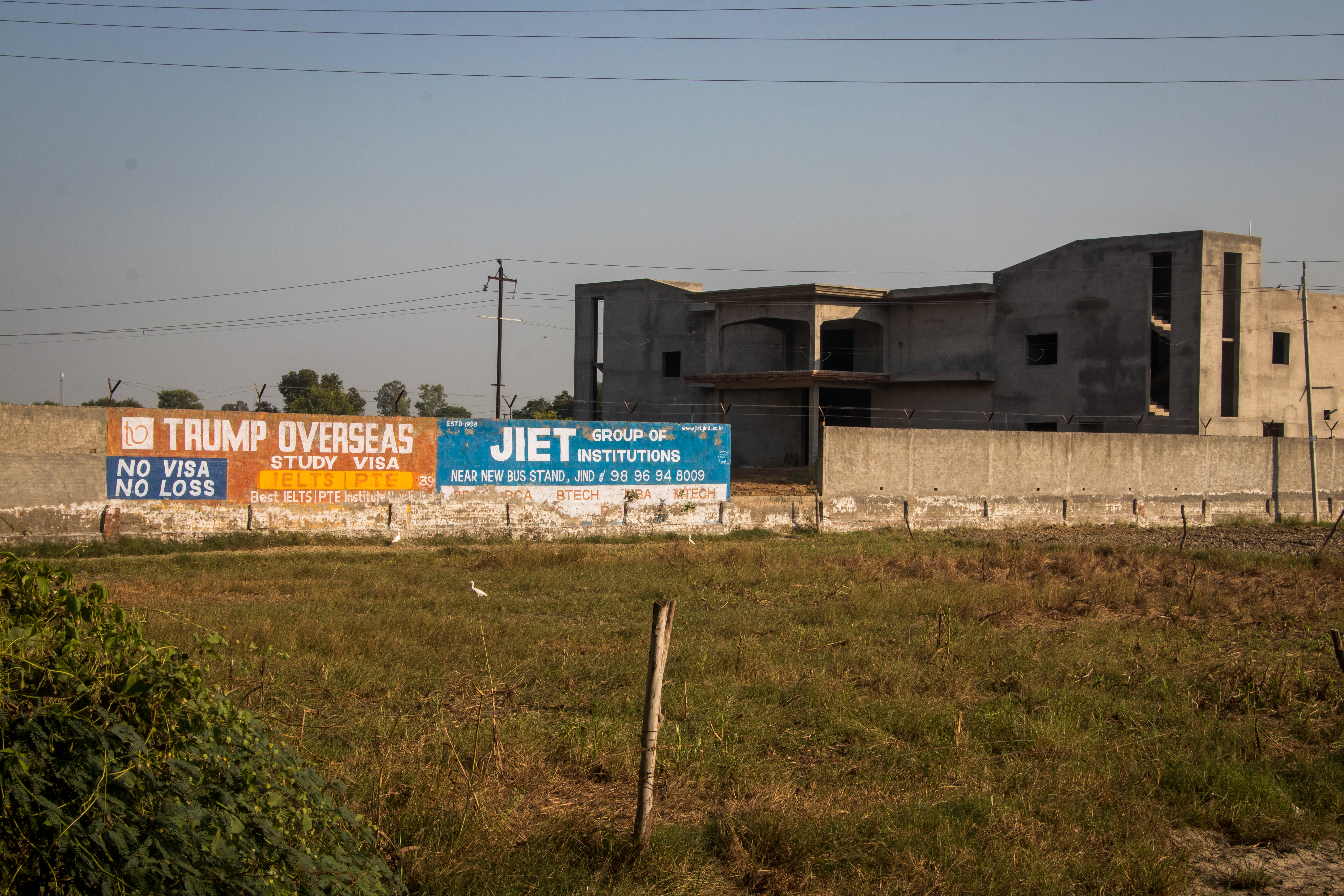 This image shows ads of foreign consultants painted on the boundary walls of an under-construction building near Taloda village.