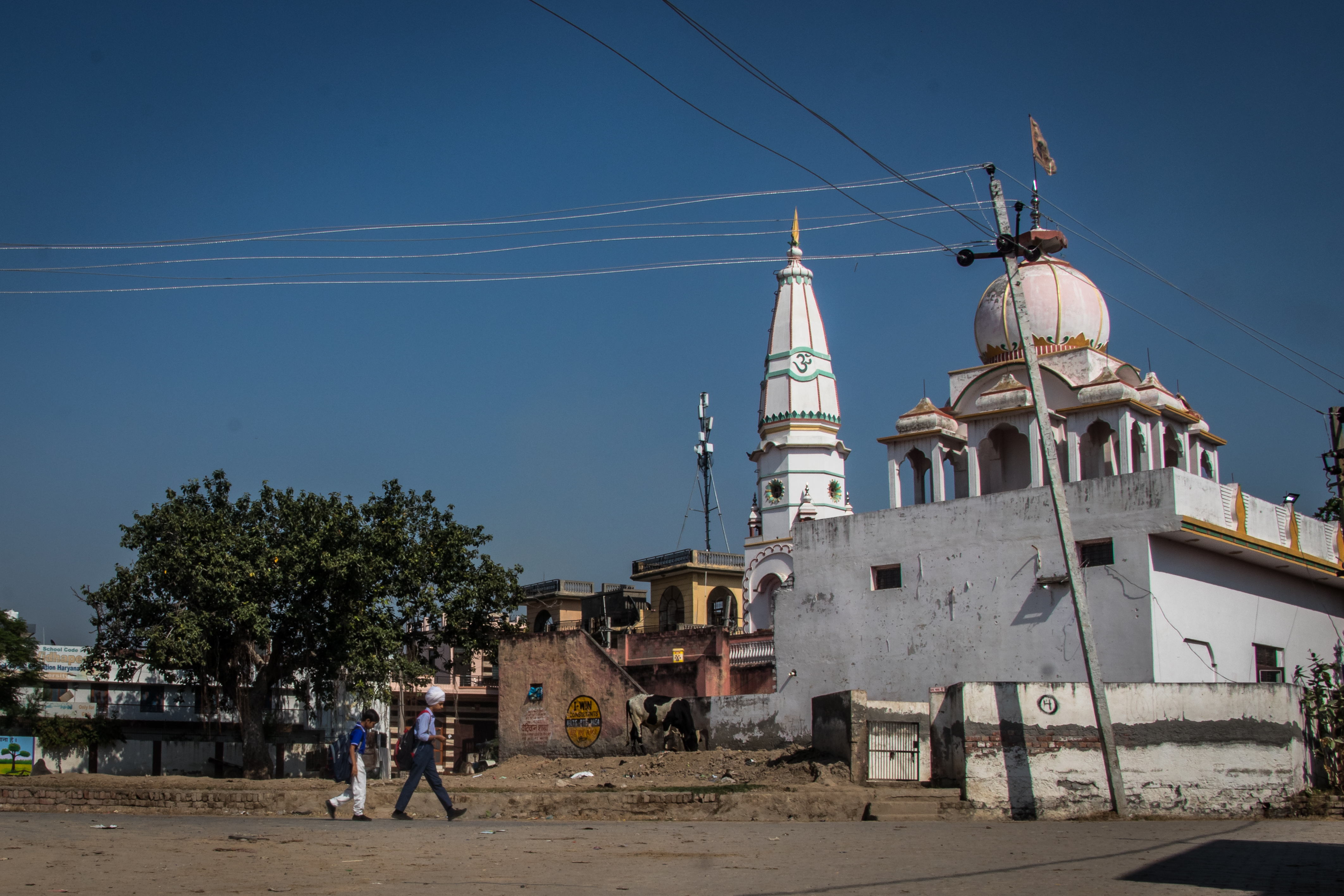 This image shows boys in school uniform walking past a deserted neighbourhood at Dhatrath village in Jind, Haryana. 