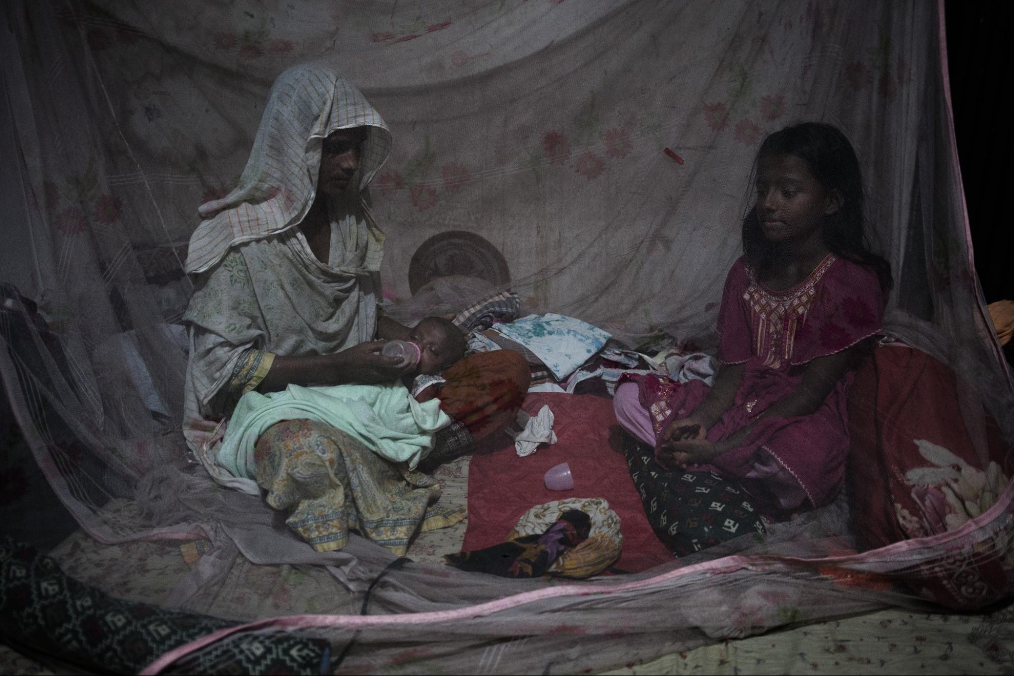 This is an image of Mosammat Shirin, another slum resident, with her daughter and granddaughter inside a mosquito net at their home.