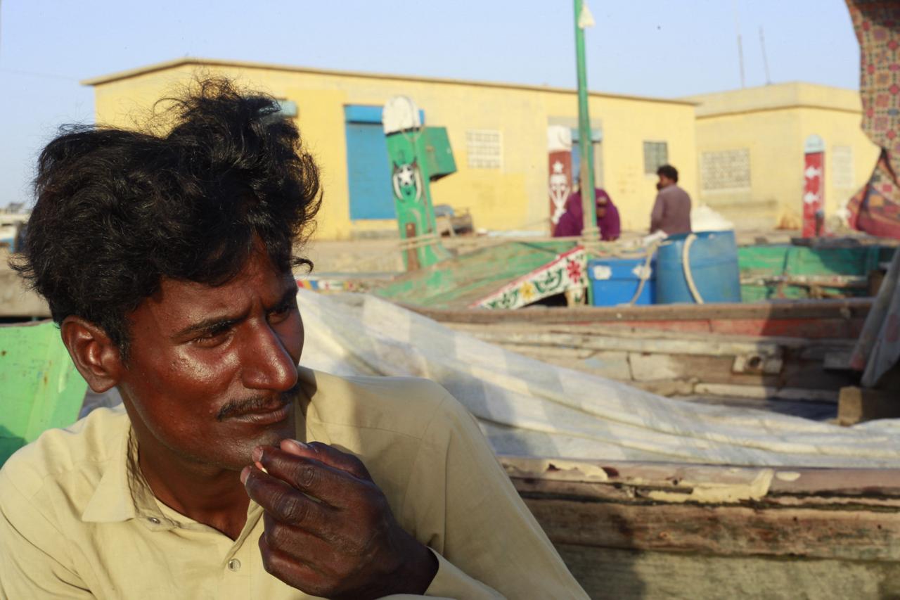 The image shows Mubeen Machi waiting for a boat captain.
