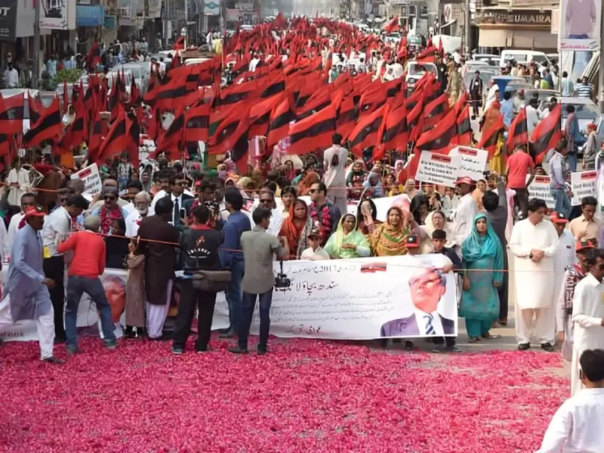 The front view of protest of Awami Tehreek’s 2017 march in Tharparkar, Pakistan with people holding banners and a lot of red and black striped flags.. Photo: Awami Tehreek/Earthwise